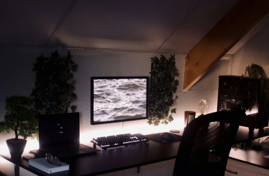 Lampe d’appoint lumineuse circulaire émise d’un halo chaud, posée sur une étagère avec plantes et objets décoratifs. Inclut le cadre de l’éclairage dans une pièce cosy.