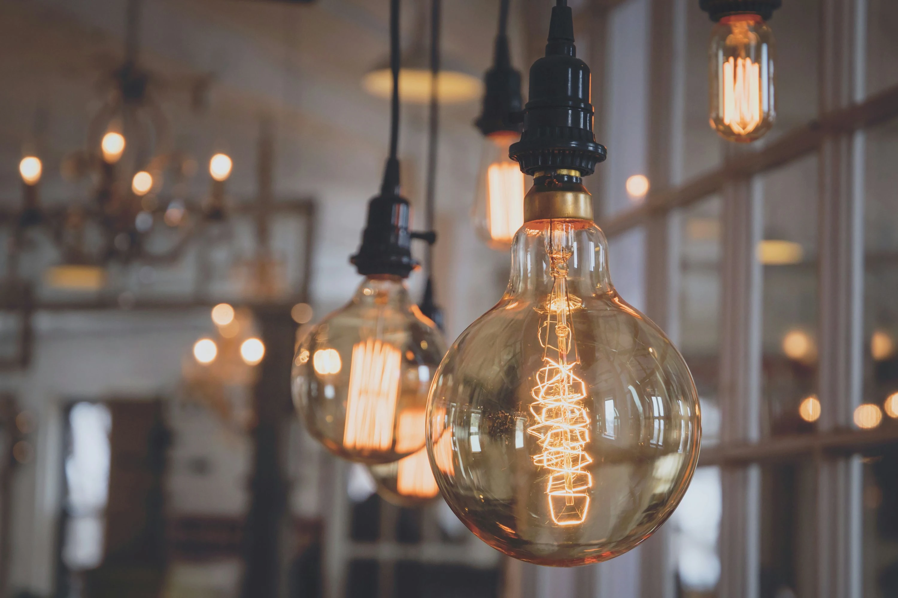 Deux personnes évaluent une ampoule LED: l’homme tient une ampoule et explique, la femme pointe un échantillon de couleurs sur une planche. Ils discutent pour choisir une ampoule LED adaptée à la maison.